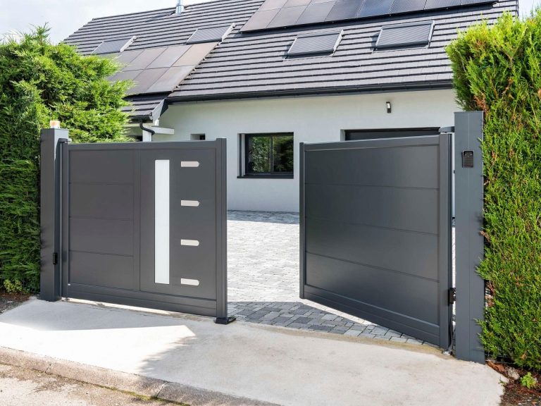 Entrée d'une maison avec des portails gris et un jardin bien entretenu.